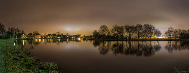 由阿姆斯特丹的河流和树木背光的和平全景视图