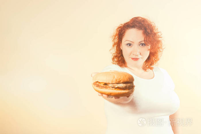 大女人吃快餐.红头发的胖女孩汉堡.不健康食物概念以加大小女性