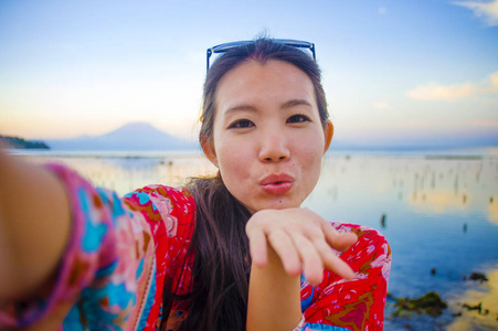 华丽的美丽和快乐的亚洲韩国或中国妇女的自画像20s 在异国风情的热带海滩上拍摄自拍照片与手机摄像机