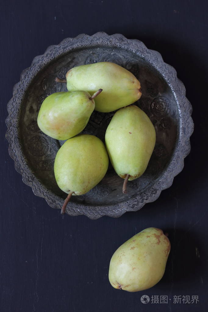 在黑色背景下的盘子里的梨