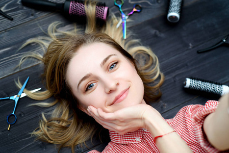 自拍照片的快乐微笑的年轻女子在格子衬衫与美发工具在她的