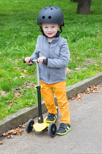 小男孩用黄色滑行车在公园