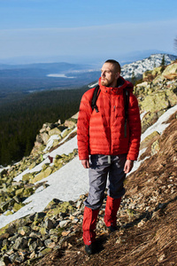 徒步旅行者带着背包穿着暖和的衣服站在雪山上的雪坡上背景上