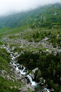 Transfagarasan 在罗马尼亚的绿草和石头中有瀑布的山河