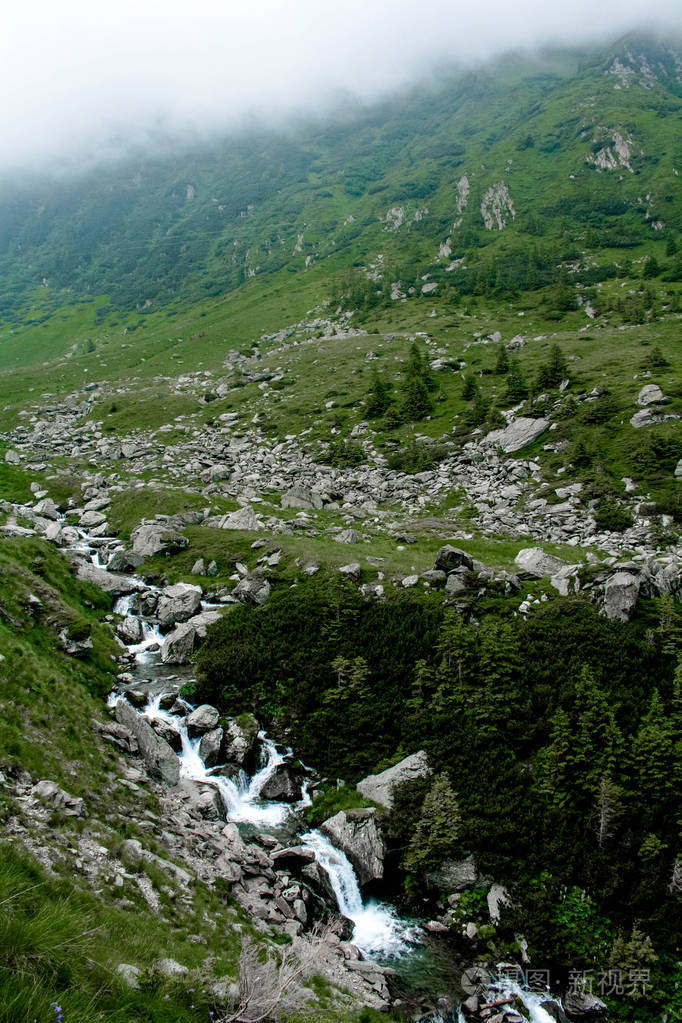 Transfagarasan 在罗马尼亚的绿草和石头中有瀑布的山河