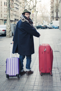 年轻人在帽子和外套在城市街道与旅行袋子在冬天时间