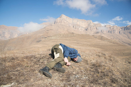 一个带着帽子和胡子的游客躺在地上, 在山上感觉很不好.失去知觉的人.