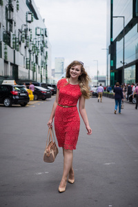 在女孩穿着珊瑚走着一只手提包间商务中心的摩天大楼