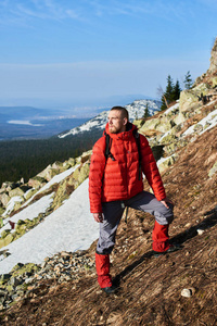背包在红色夹克与背包站立在倾斜与山在背景上