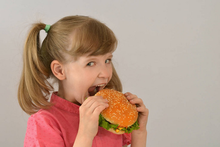 小女孩吃三明治。汉堡包, 快餐