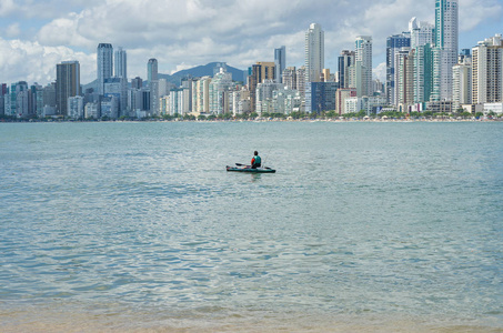一个年轻人在巴西海滩上独木舟漫步。钓鱼独木舟