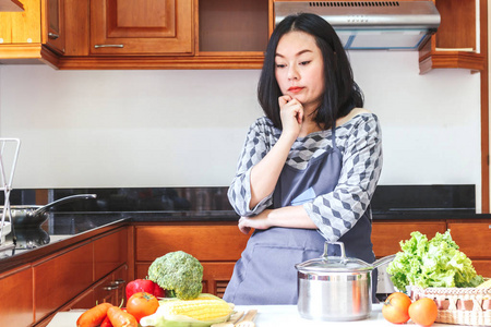 厨房里用新鲜蔬菜烹调的妇女