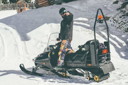 胡子 snowboarded 中毒在雪地车上。雪地巡逻队背景模糊。水平