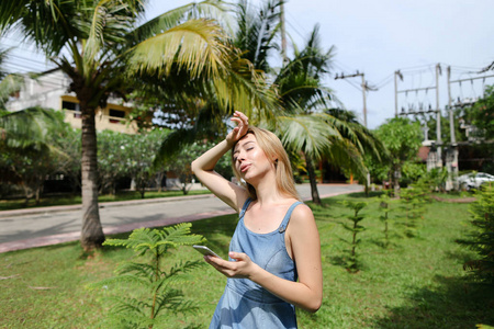 年轻妇女站在智能手机与手掌在后台