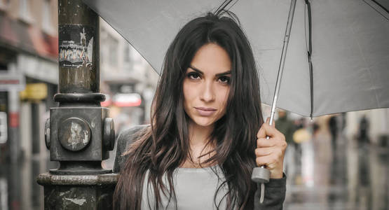 一把伞在城市街道上的雨下的女人