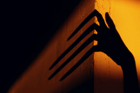 墙上有奇怪的影子. 可怕的阴影.抽象背景.墙上一只大手的黑色影子.