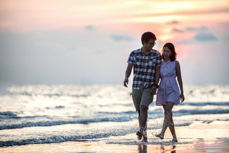 夫妻在海滩上散步.走在海滩上的年轻快乐异国情侣照片