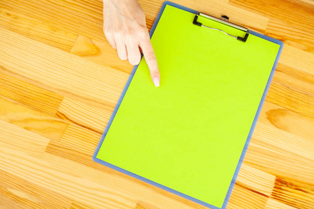 办公室手拿着一个带绿色纸的文件夹在木桌的背景上。Copyspace。文本位置