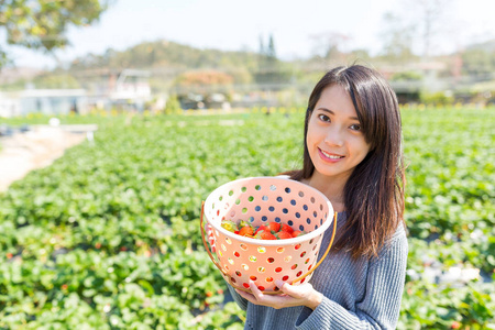 年轻女子捧着一篮草莓