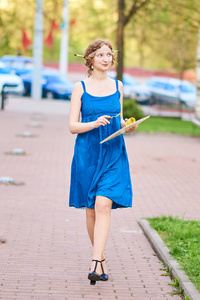 美丽的女孩艺术家在街上的蓝色礼服, 微笑着, 在她手中的流苏和调色板