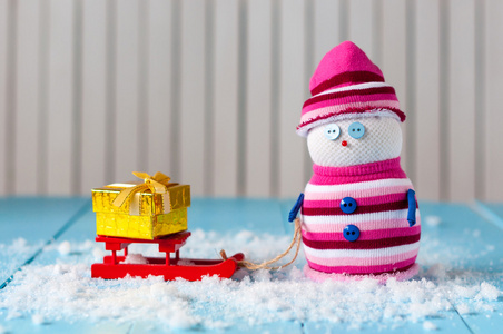 手工装饰雪人与红色雪橇和礼物盒上的结扎。