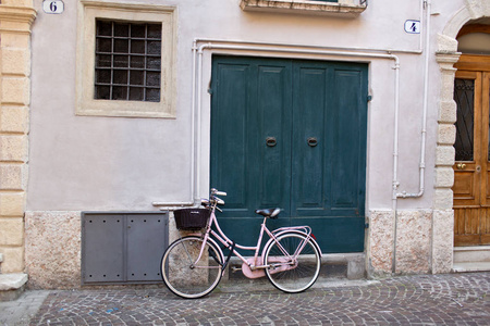 粉红色自行车的日间看法与篮子停放在绿色门附近照片