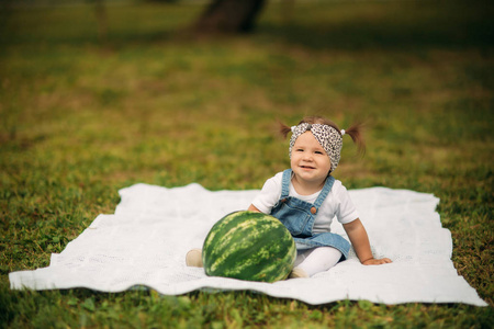 小女孩坐在公园里的格子和吃西瓜