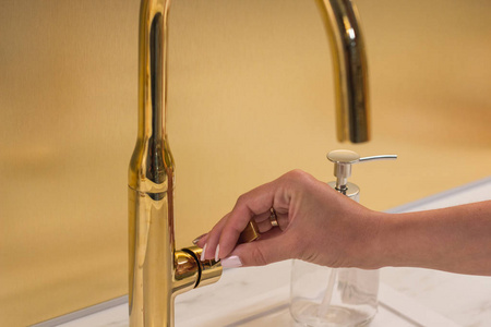 女孩打开水龙头洗手.照片