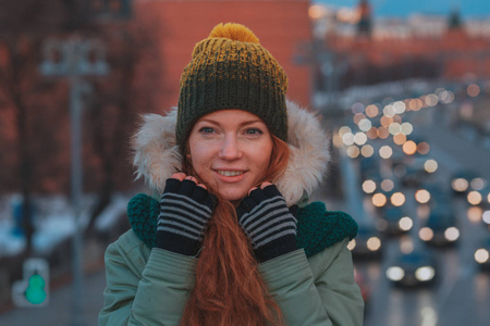 美丽的冬天冬天下雪的景色的年轻女子的画像。漂亮的红发女孩走在冬天晚上市