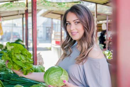 购买新鲜的有机蔬菜，在街边市场的女人。年轻女子买菜在绿色市场