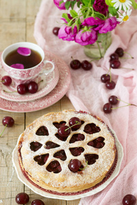 一种樱桃派, 用一杯茶一束鲜花和成熟的樱桃浆果装饰着心形的装饰。复古风格, 选择性聚焦