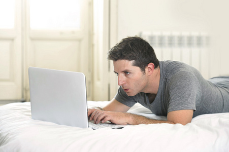 躺在床上或沙发上用电脑工作的年轻人
