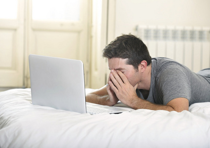 躺在床上或沙发上用笔记本电脑工作的年轻人