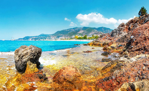 在土耳其的安塔利亚, 阳光明媚的夏日, 岩石热带海滩上的美景令人惊叹。土耳其海景, 海岸线上有山脉和岩石。湛蓝的天空, 海和热带