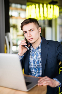 年轻的自由职业者使用笔记本电脑和电话与客户交谈