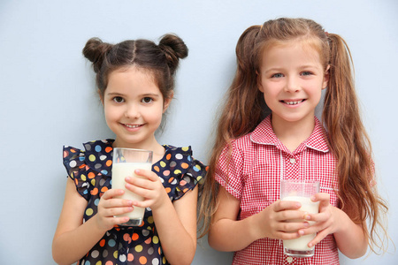 两个小女孩的肖像在蓝色背景下的牛奶杯