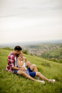 爱的情侣坐在山上的草地上拥抱着