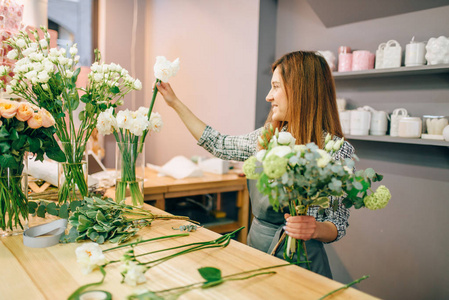 女花商把花放在花瓶里, 新鲜的花束准备过程。花卉企业业主在工作场所