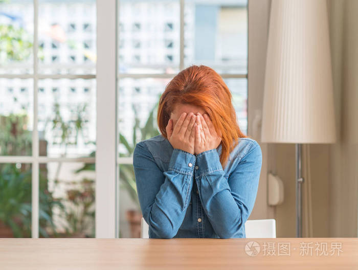 红发女人在家里带着悲伤的表情捂着脸, 一边哭着.抑郁症概念
