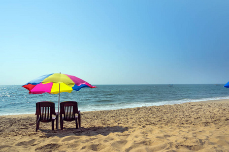 两个休闲椅撑一把伞在沙滩上图片