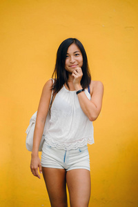 一个运动, 可爱的中国亚洲女孩的肖像穿着舒适, 微笑着对一个黄色背景在演播室的相机