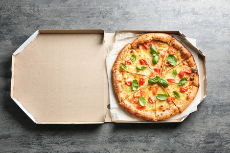 纸箱盒与美味的比萨饼玛格丽特灰色背景