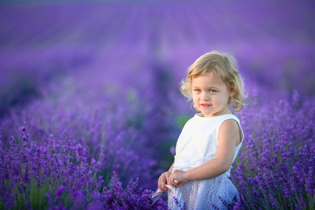 美丽的小女孩摆在薰衣草田野捧满鲜花的篮子