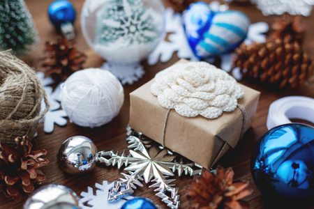 圣诞节和新年背景与礼物, 丝带, 球和不同的蓝色装饰在木制背景。礼品包装在工艺纸与手工制作的钩针花。diy 包装礼物的方法