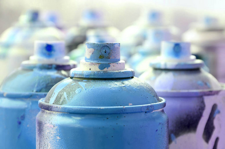 很多肮脏的和二手的烟雾罐的明亮的蓝色油漆。具有浅景深的宏照片。喷雾喷嘴选择性聚焦