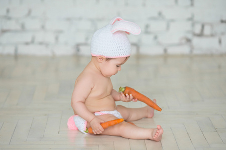 一个穿着兔子耳朵坐着吃东西的可爱婴儿的肖像。
