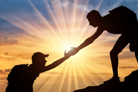 自由之手一个男性登山运动员的剪影, 在一个团队与一个合作伙伴, 给他