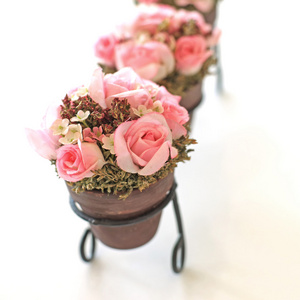 粉红色的玫瑰人造花在花盆上白色孤立