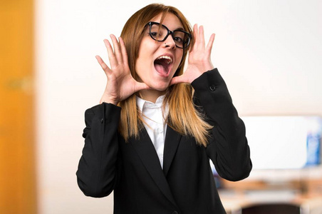 年轻的商界女人制作惊喜手势在不专心背景的办公室