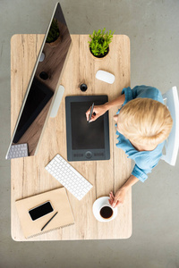 女性 teleworker 的高视图使用图形平板电脑在桌上的咖啡, 智能手机和电脑在家里的办公室